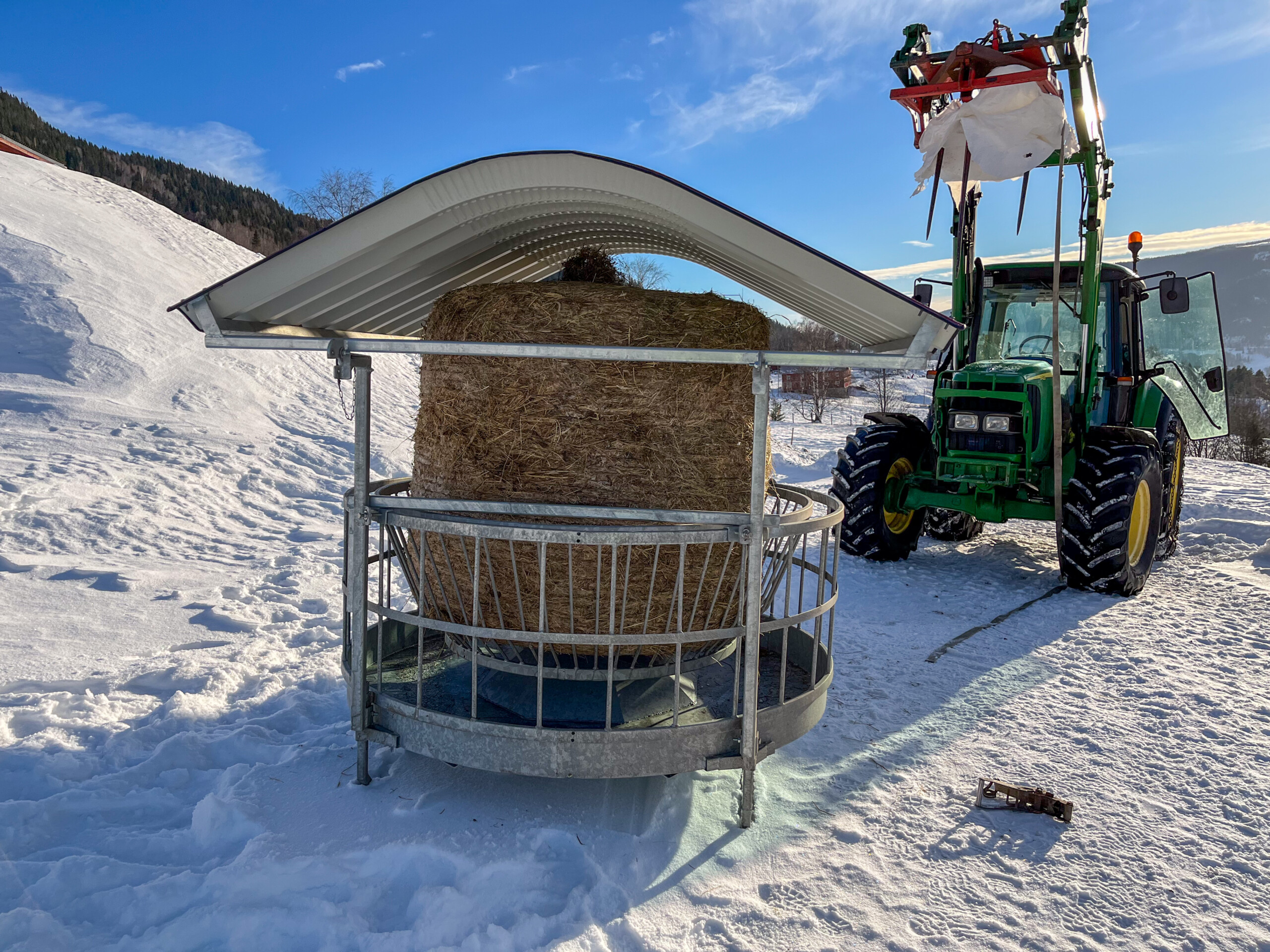 Ilegg av rundbal med traktor i rundbalshäck med tak för får och get